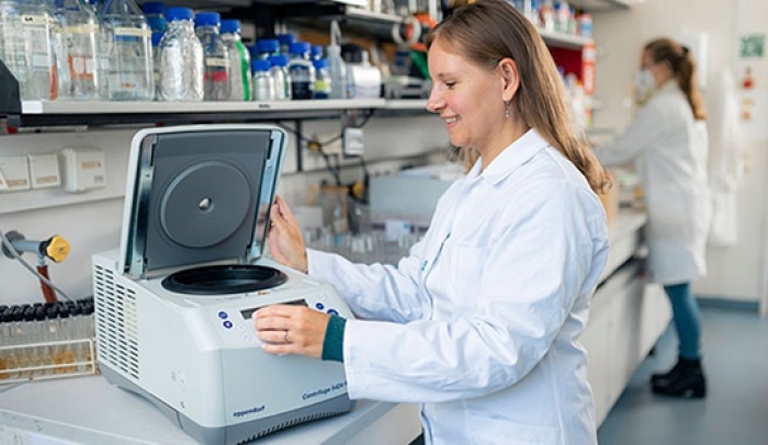 woman in lab holding opened lid of centrifuge