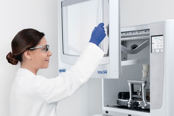 Female scientist opens the door of the Eppendorf Innova S44i lab shaker.