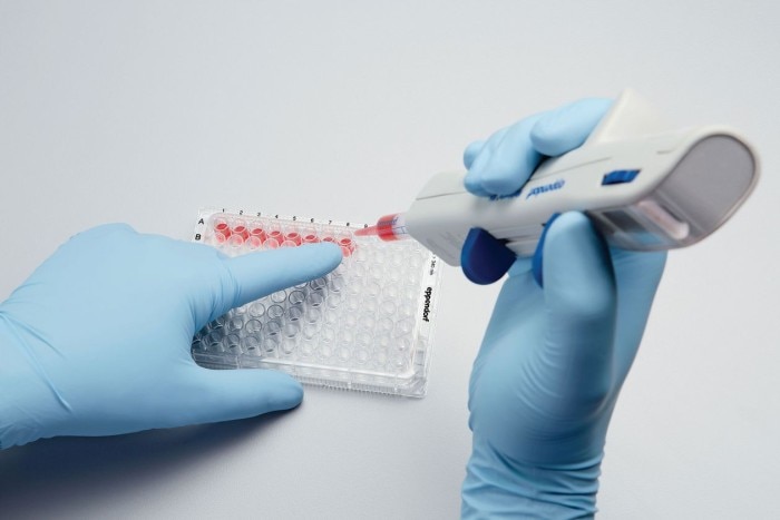 Scientist uses electronic dispensing tool to fill sample aliquots into microtiter plate.