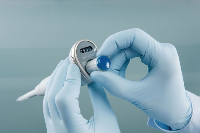 Scientist adjusting the volume setting of a pipette.