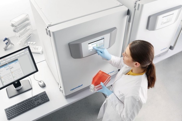 A scientist is programming a CO2 incubator ergonomically located on the lab bench.