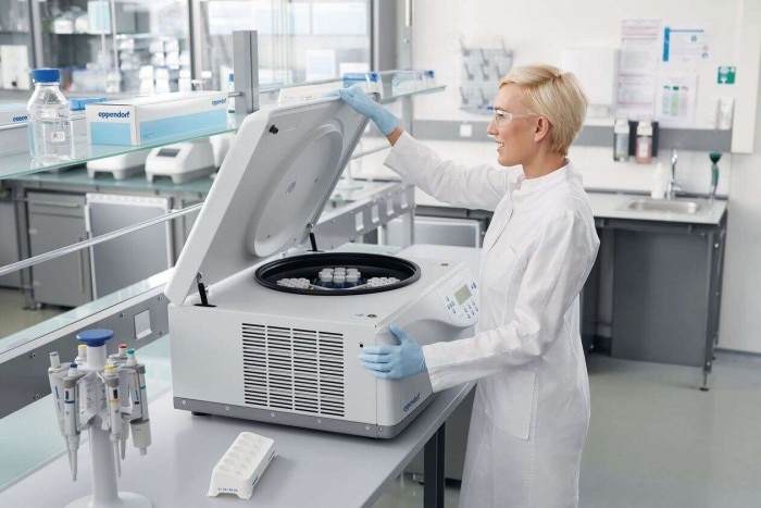 Scientist transfers some sample vessels into a centrifuge.