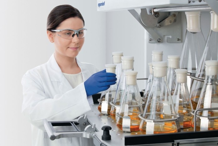 Scientist handles some sample flasks by easily pulling out the shaker platform.