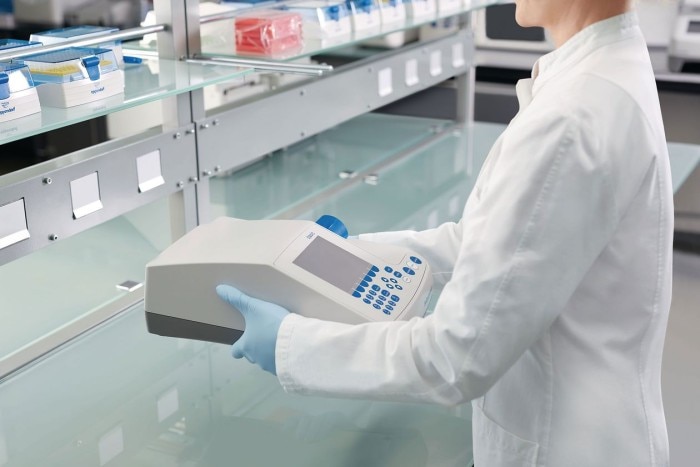 A scientist is holding an instrument in the laboratory.