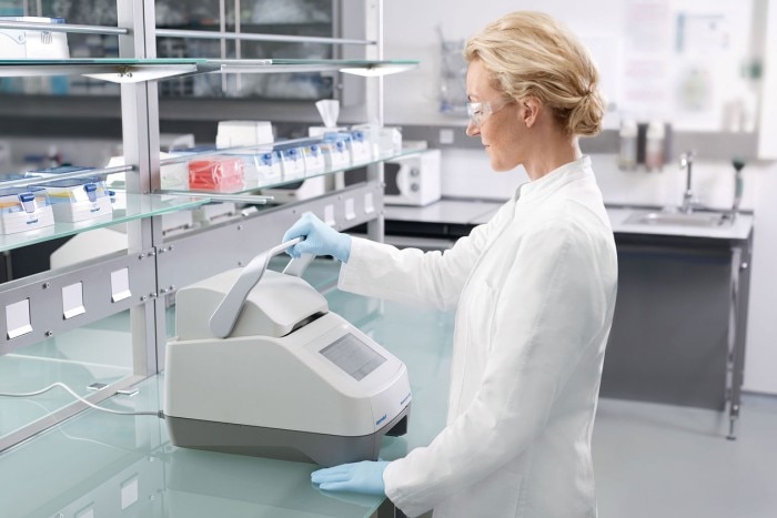 Scientist working in the laboratory, closing the heated lid of the Eppendorf PCR cycler.