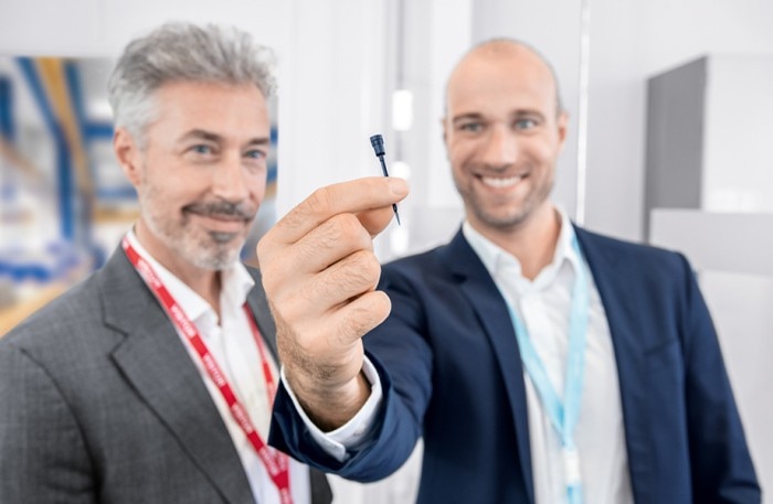 Two men holding a black OEM pipette tip as customized solution with toolshop in the background.