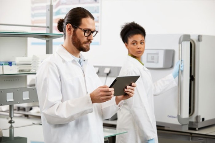 Man in the laboratory using a mobilephone to remotely monitor biological shaker.