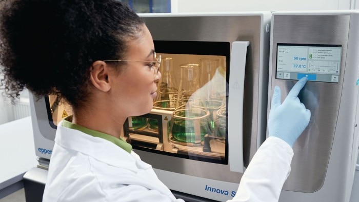 Woman in the laboratory is changing the settings of the biological shaker Innova® S44i via the VisioNize touch interface