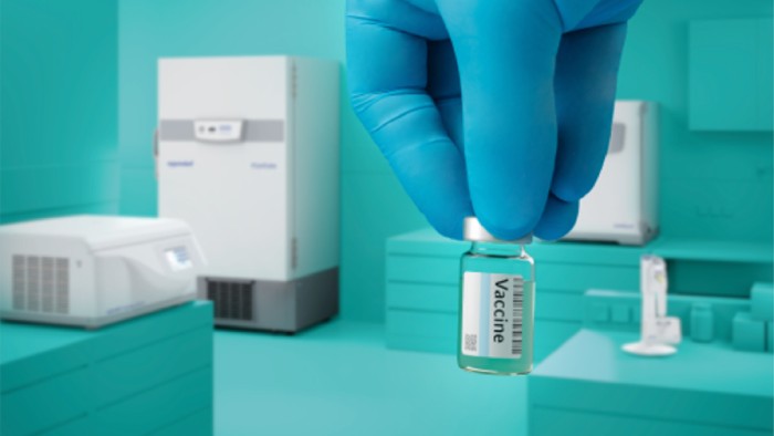 Hand holding vaccine vial against the background of a laboratory