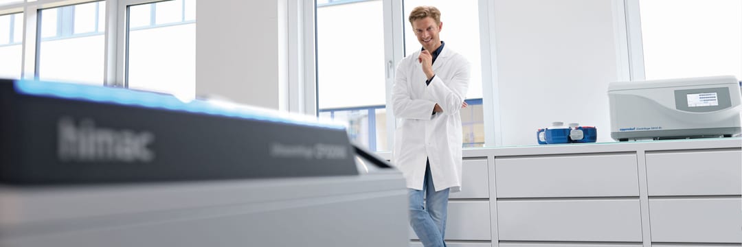 Lab scene with male Lab Assistant in the background and blurry eppendorf Himac Ultracentrifuge in the foreground